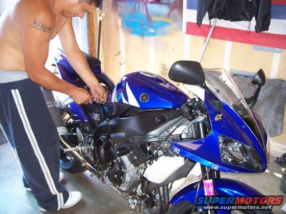 Guy working on a blue Yamaha motorcycle in a garage