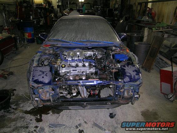 Blue car front view, hood open, engine exposed. Some parts removed
