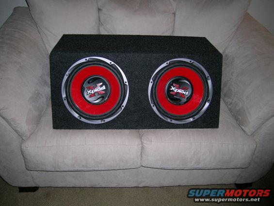 Dual Sony Xplod subwoofers in a black enclosure on a couch