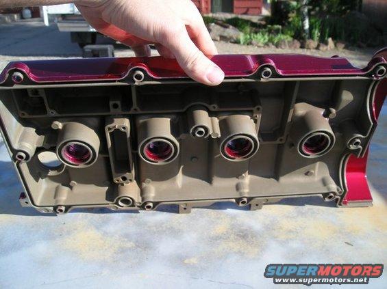 Engine valve cover with red paint, held by a hand