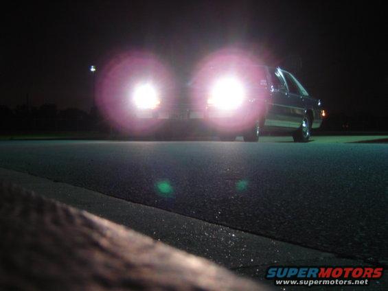 1988 Ford Crown Victoria LTD with headlights on, seen from a low angle at night