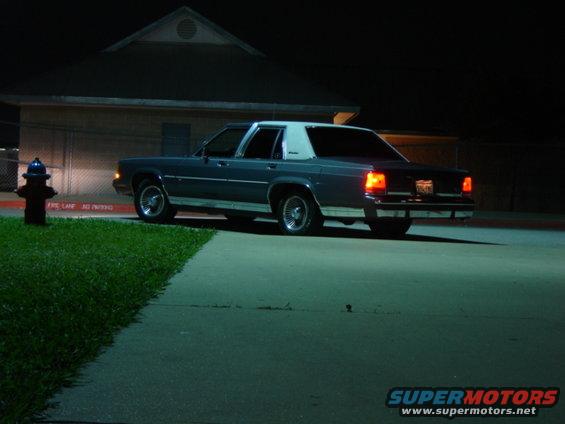 Dark blue sedan with a white vinyl roof parked at night, rear view