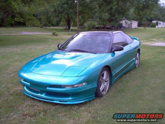 Teal 1993 Ford Probe with black roof and aftermarket body kit parked on grass