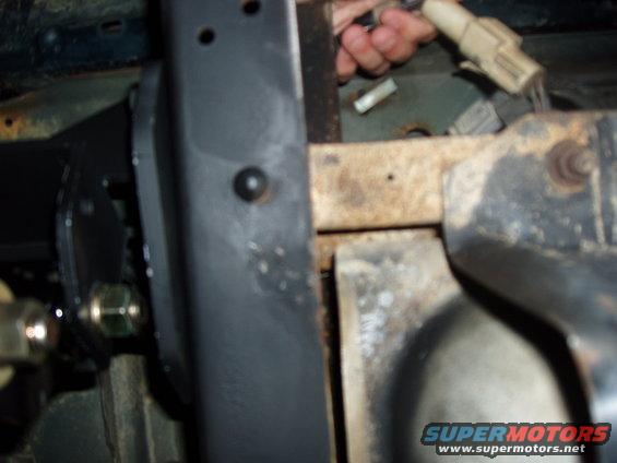 Close-up of vehicle frame with wiring harness and bolts