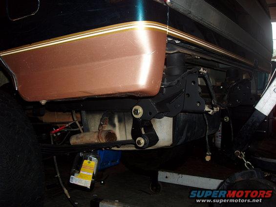Underside of a vehicle showing suspension components and fuel tank. Has a two-tone paint job with a gold stripe