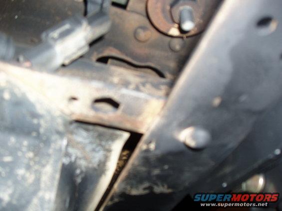 Close-up of vehicle frame and suspension parts. Some rust visible