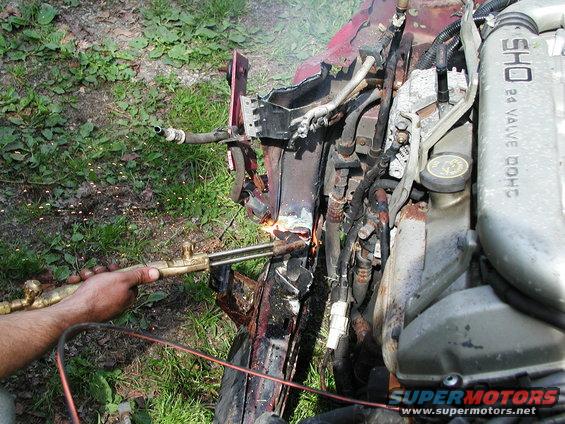 Cutting engine components with a torch; "SHO 24 VALVE DOHC" visible on engine cover