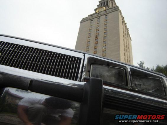 Car grille and headlights with a tower in the background