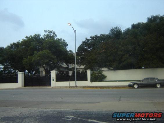 Dark sedan parked on the side of the road, viewed from the side. The car has a boxy shape and appears to be from the early 1990s