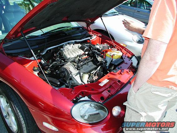 Red car with hood open showing engine. Another car is visible behind it