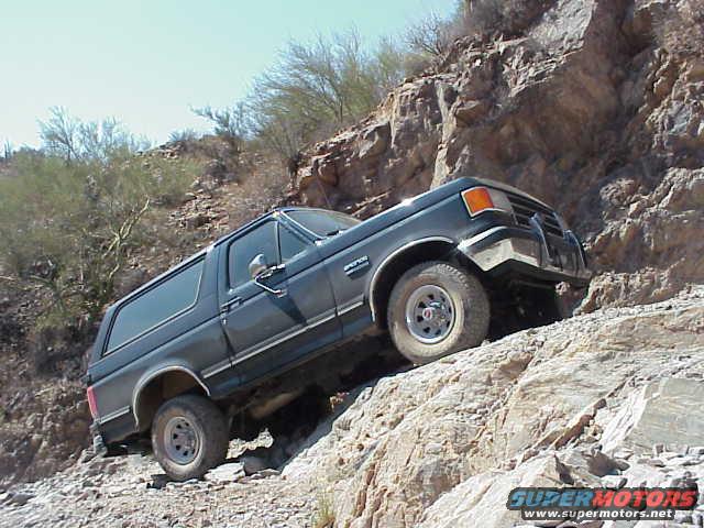 Dark blue 1990 Ford Bronco climbing a rocky hill