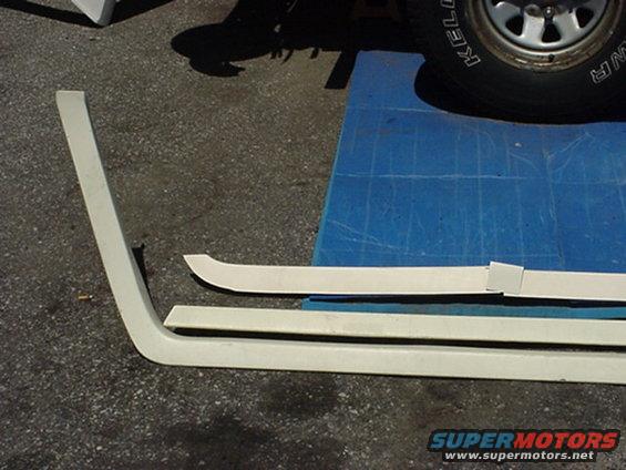 White plastic trim pieces and a tire with 'KELLY' visible, on a blue mat