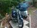 1976 Harley-Davidson Super Glide - Two motorcycles are parked outdoors, one is covered by a tarp, the other is uncovered.