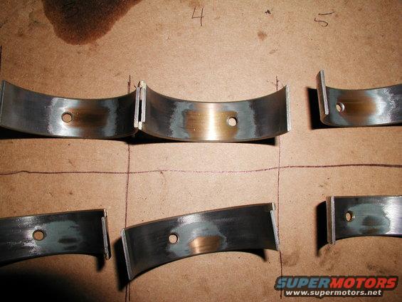 Engine rod bearings laid out on cardboard with numbers 4 and 5 written above