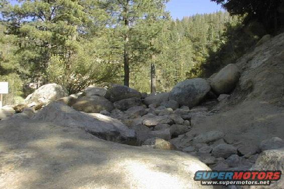 rocky path with trees and a sign