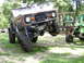 1995 Ford Bronco - A Ford Bronco is being lifted by a tractor loader in a grassy, wooded area.