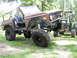 1995 Ford Bronco - This heavily modified Ford Bronco sits high off the ground, with a tractor visible behind it.