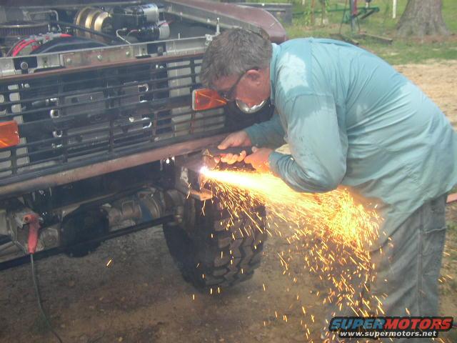 1995 Ford Bronco front end with a man welding, sparks flying, off-road tires visible