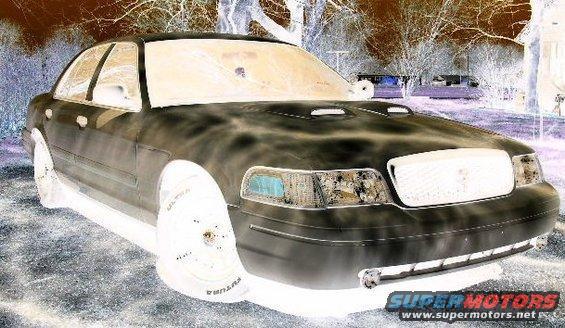 Front 3/4 view of a 2001 Ford Crown Victoria. It has a chrome grille and hood scoops