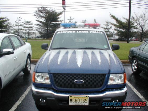 Blue police truck with red and blue lights on top. Medford Lakes Police text on windshield. White jagged stripes on hood