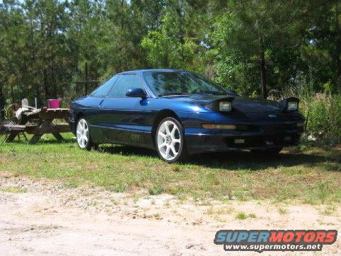 Blue 1993 Ford Probe GT coupe with white wheels, parked outdoors on grass
