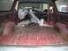 1981 Ford Bronco - The interior of a red SUV is shown, with the cargo area and dashboard covered in protective plastic sheeting.