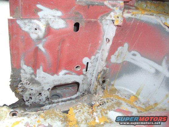 Red painted metal with rust and holes, showing signs of repair and corrosion
