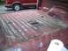 1981 Ford Bronco - Interior of a red truck bed shows signs of wear and tear, with another vehicle visible in the background.