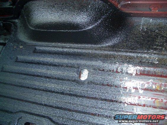 Interior floor with textured black coating and red metal visible