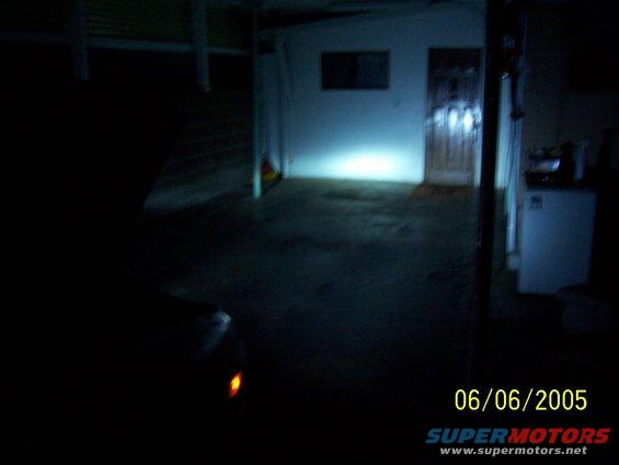 Car headlight illuminated in dark garage