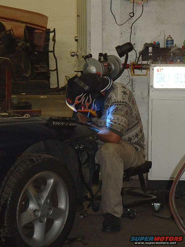 1994 Ford Probe fender and wheel with a person welding nearby