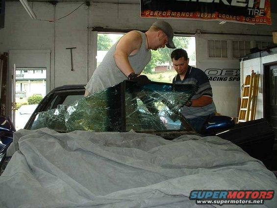 1994 Ford Probe with shattered windshield being removed by two men in a garage