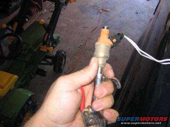 Hand holding a fuel injector with wires attached