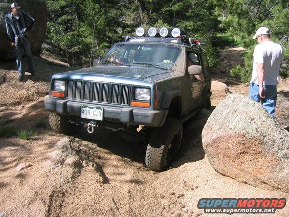 1997 Jeep Cherokee navigating a rocky trail with people watching