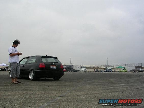Black Volkswagen Golf GTI parked on asphalt, person looking at phone