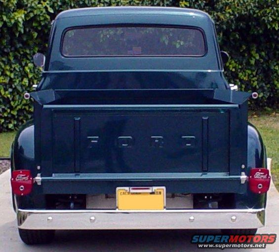 Rear view of a dark green 1956 Ford F-100 pickup truck with a yellow California license plate
