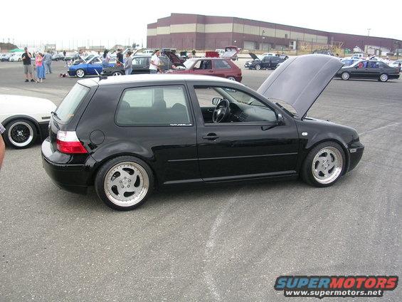 Black Volkswagen Golf GTI with hood open, parked at an outdoor car show