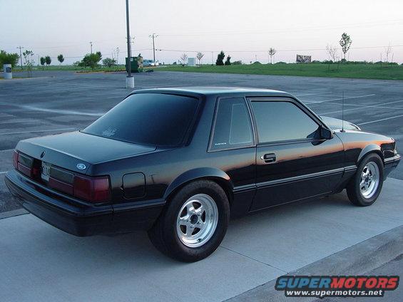 Black coupe car with aftermarket wheels parked on concrete
