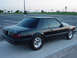 1990 Ford Bronco - A black coupe car with aftermarket wheels is parked in an empty lot.