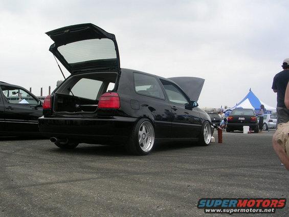 Black hatchback with trunk and hood open, lowered suspension, chrome wheels