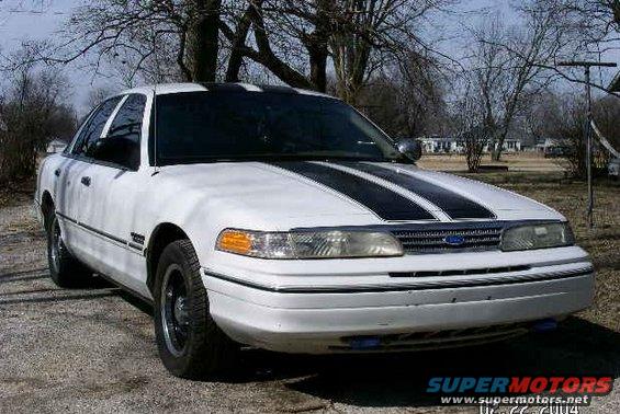 White 2001 Ford Crown Victoria with black racing stripes on the hood and roof, parked outdoors