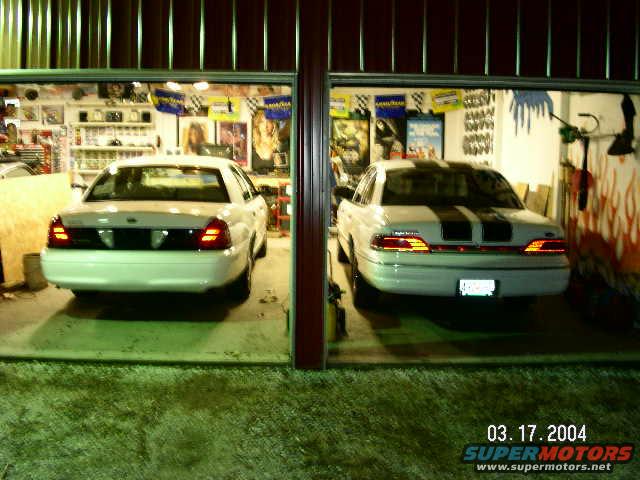 Rear view of two white 2001 Ford Crown Victorias in a garage