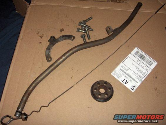Engine dipstick tube, dipstick, bolts, and a pulley on cardboard