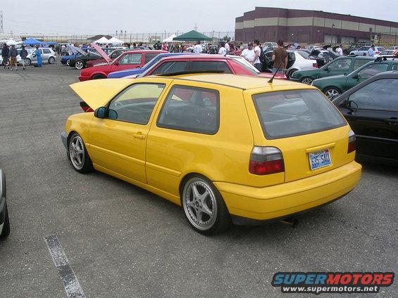Yellow Volkswagen Golf GTI parked at an outdoor car show. License plate reads 635-SAU