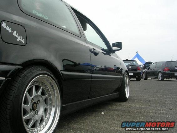 Black hatchback side view with custom wheels and 'Rat-Stylz' sticker