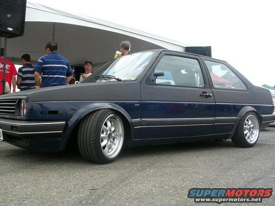 Dark blue hatchback with aftermarket wheels, lowered stance