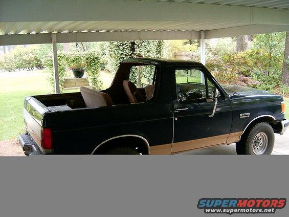 Dark blue 1991 Ford Bronco with tan lower body trim, parked under a carport