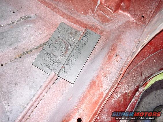 metal plates welded onto red car body, likely for repair