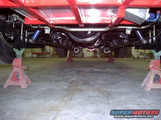 Undercarriage of a vehicle on jack stands, showing suspension and exhaust components
