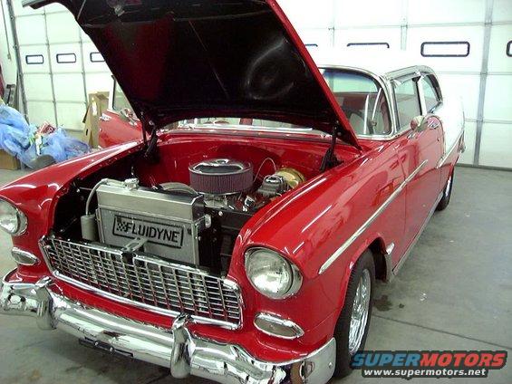 Red and white 1955 Chevrolet sedan, front view, hood open revealing engine and Fluidyne radiator